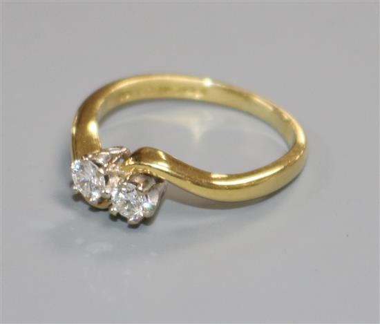 A modern 18ct gold and two stone diamond crossover ring, size J.